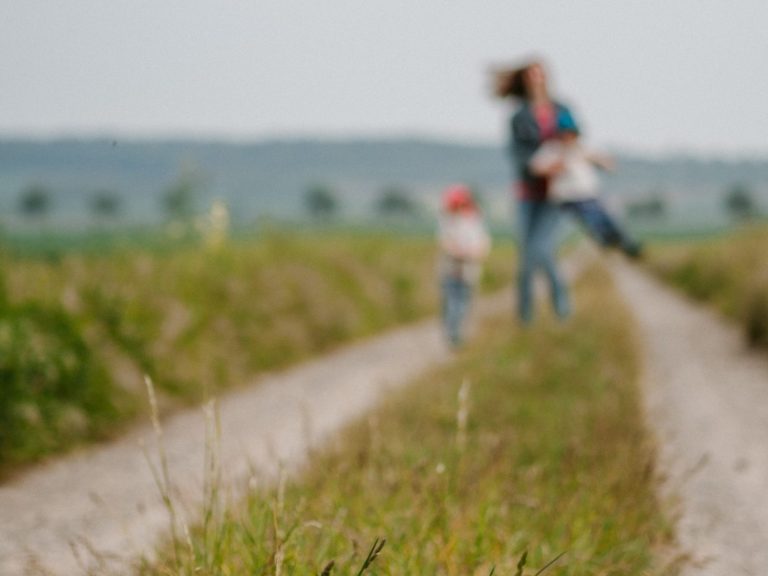 Foto: Mutter mit zwei Kindern auf einem Feldweg.