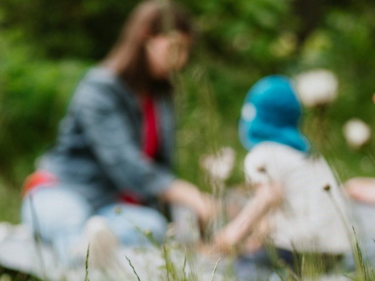 Foto: Mutter beim Picknick mit ihrem Kind auf einer grünen Wiese.